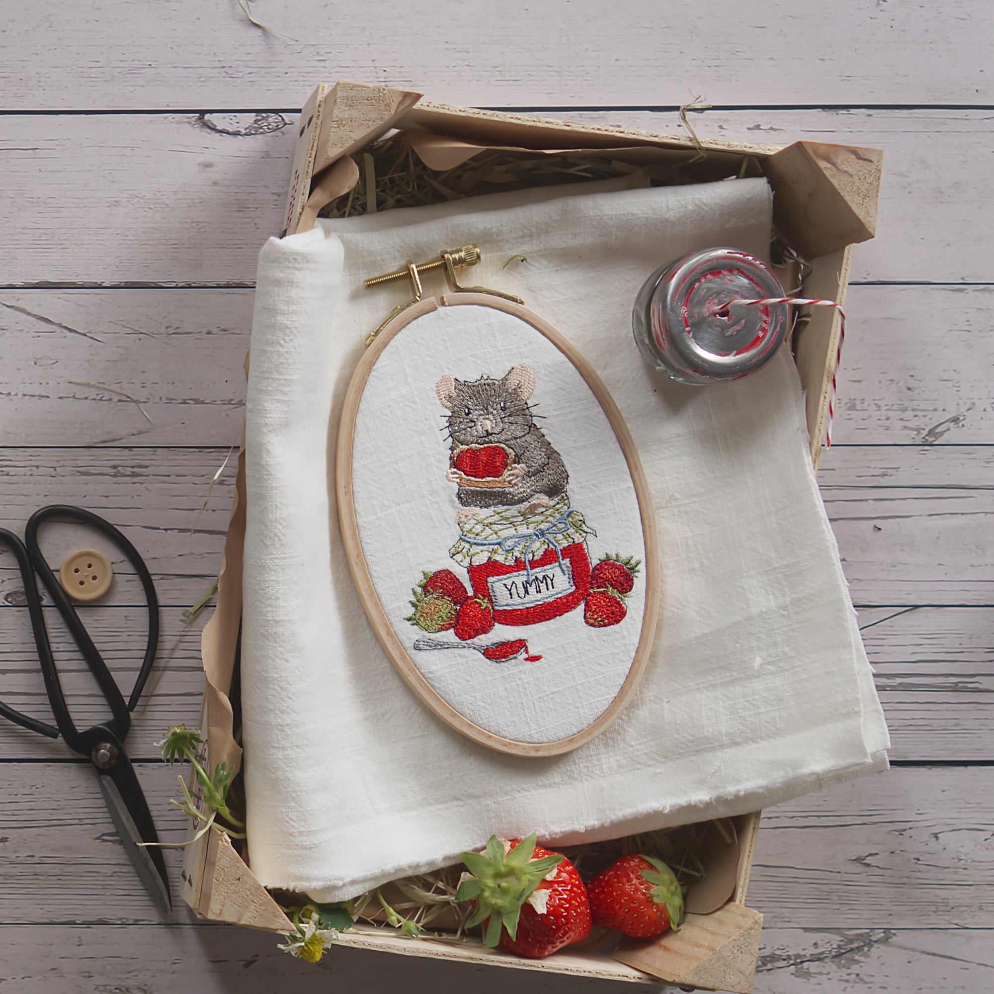 Stickdatei Maus mit Erdbeermarmelade im Stickrahmen. Kleine Maus sitzt auf einem Marmeladenglas mit Erdbeeren. Sommerliche Maschinenstickerei aus der Erdbeermäuse Serie.