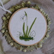 Stickdatei Schneeglöckchen, zartes Frühlingsmotiv mit feiner Blüte und Gräsern, gestickt auf heller Leinenware im Stickrahmen