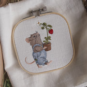 Stickdatei Maus mit blauer Latzhose trägt einen Blumentopf mit Erdbeerpflanze. Sommerliches Gartenmotiv aus der Erdbeermäuse Serie.