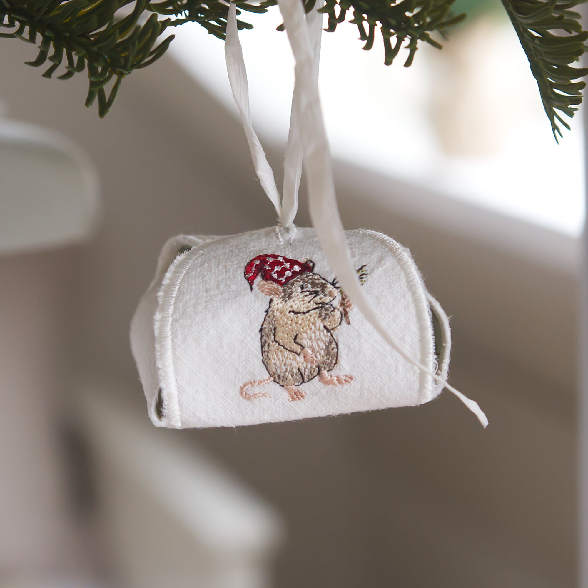 Gestickte Wichtelmaus mit roter Mütze und Tannenzweig auf weißer Geschenkbox und Geschenkanhänger – ITH Stickdatei Weihnachten von Cora Design